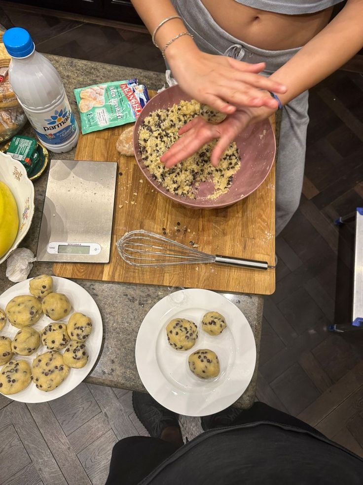 a woman is making cookies on a table with other ingredients and baking utensils