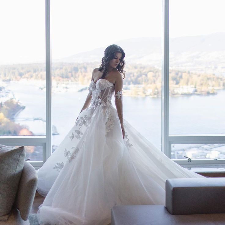 a woman in a wedding dress looking out the window