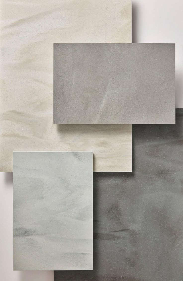 four different colors of marble tiles on a white wall, one is grey and the other is beige