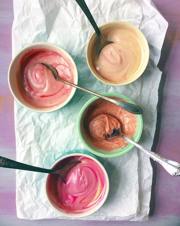 three bowls filled with different colored food on top of a white paper towel next to two spoons