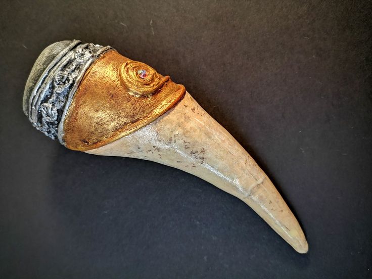 an animal's head is shown with gold and silver accents on the top part of it