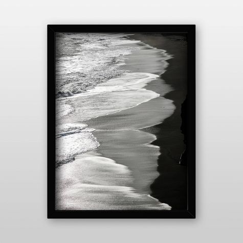 a black and white photo of the ocean with waves coming in from the shore, framed on a wall