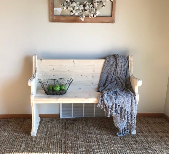 a wooden bench sitting in front of a wall with a basket on top of it