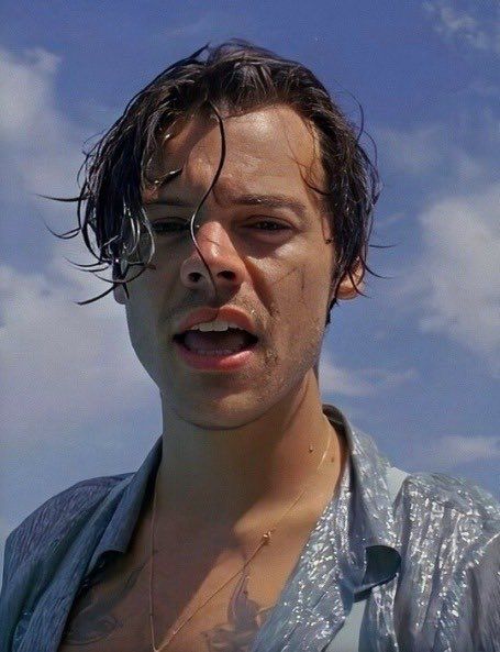 a man with wet hair standing in front of the ocean and looking off into the distance