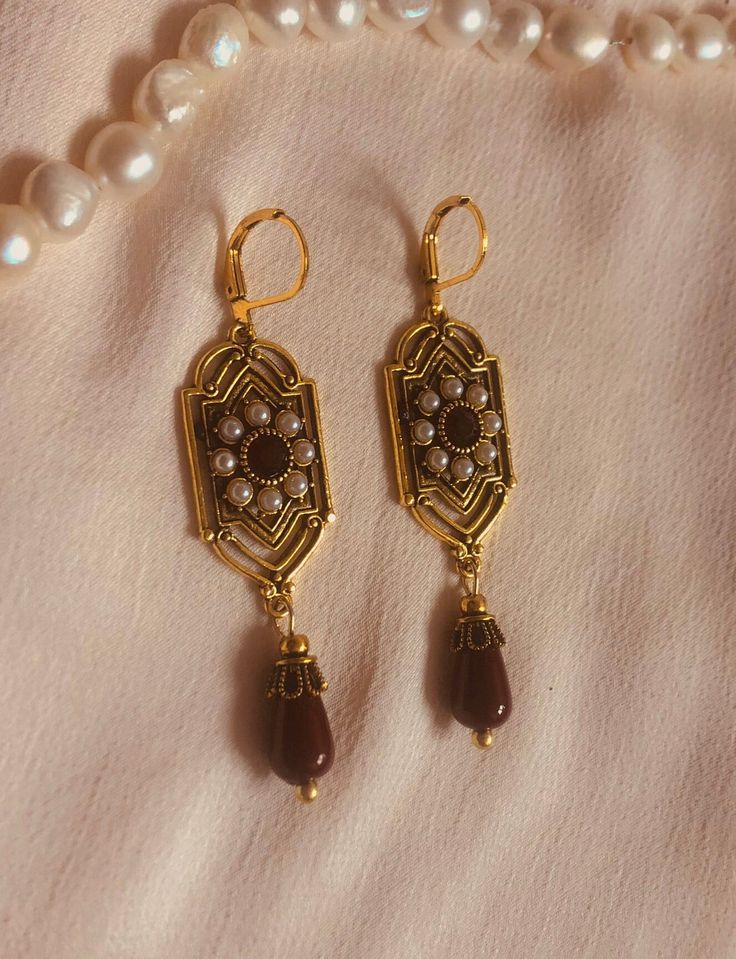 These Oriental earrings are intricately designed pieces of jewelry that have their origins in the rich cultural traditions of the Middle East, Asia and North Africa. These earrings are often characterized by their opulent and detailed workmanship, reflecting the diversity and richness of the respective cultures. Iranian Gold Jewelry, Handmade Drop Clip-on Earrings For Festive Occasions, Traditional Red Filigree Jewelry, Elegant Drop Clip-on Earrings With Latkans, Red Filigree Drop Earrings, Ornate Antique Gold Earrings For Formal Occasions, Vintage Brass Earrings For Celebrations, Vintage Earrings With Intricate Design For Celebrations, Traditional Dangle Clip-on Earrings For Formal Occasions