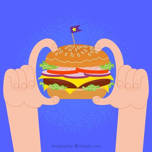 a hand holding up a large hamburger in front of the camera with a toothpick sticking out of it