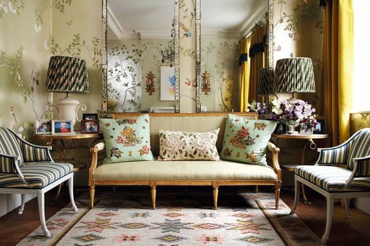 a living room with floral wallpaper and striped chairs in front of a large mirror