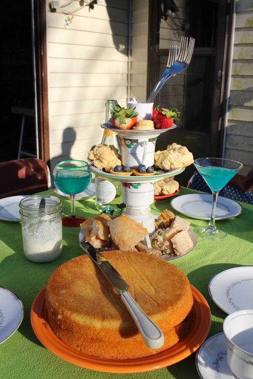 there is a cake on the table with desserts and drinks in front of it