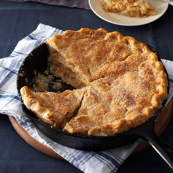 a pie sitting on top of a wooden table next to a white plate and fork