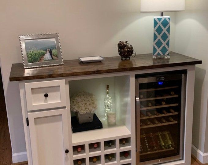 a wine cabinet with many bottles in it and a lamp on the wall behind it