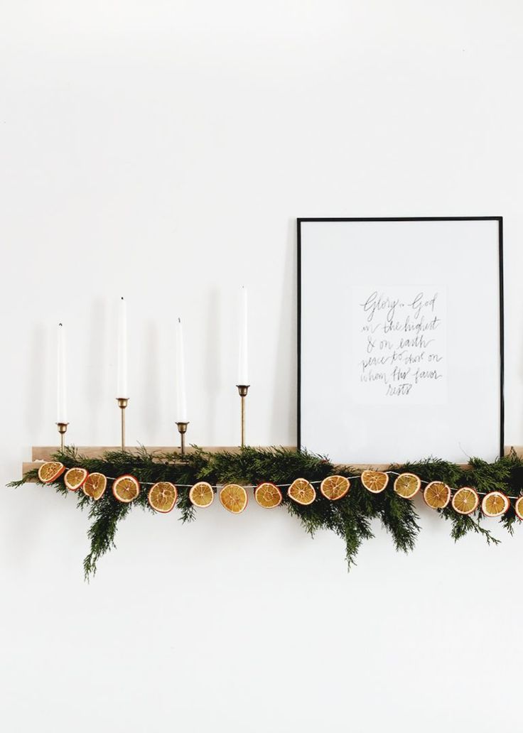 an arrangement of oranges and candles on a mantle