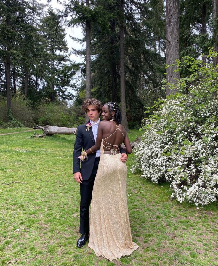 a man and woman standing in front of some trees with their backs to each other