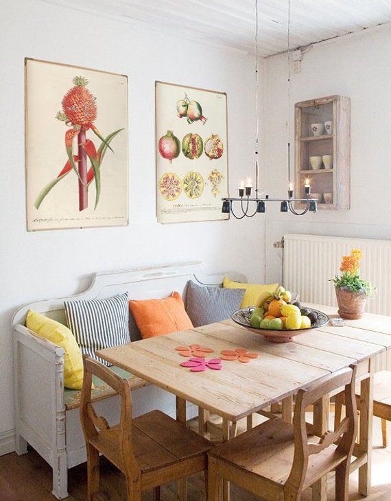 a dining room table with some fruit on top of it and two pictures above the table