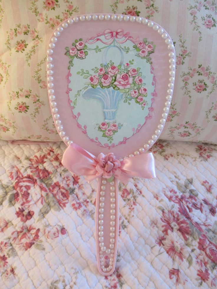 a decorative pink mirror sitting on top of a bed next to pillows and a pillow