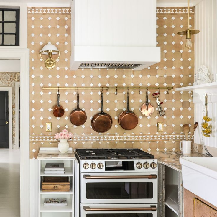 a kitchen with pots and pans hanging on the wall next to an open oven