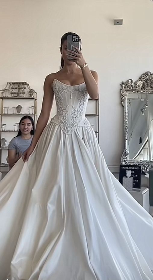 a woman taking a selfie while wearing a wedding dress in front of a mirror