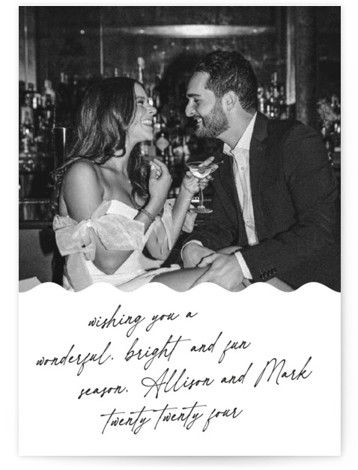 a man and woman sitting at a table with wine glasses in front of the couple