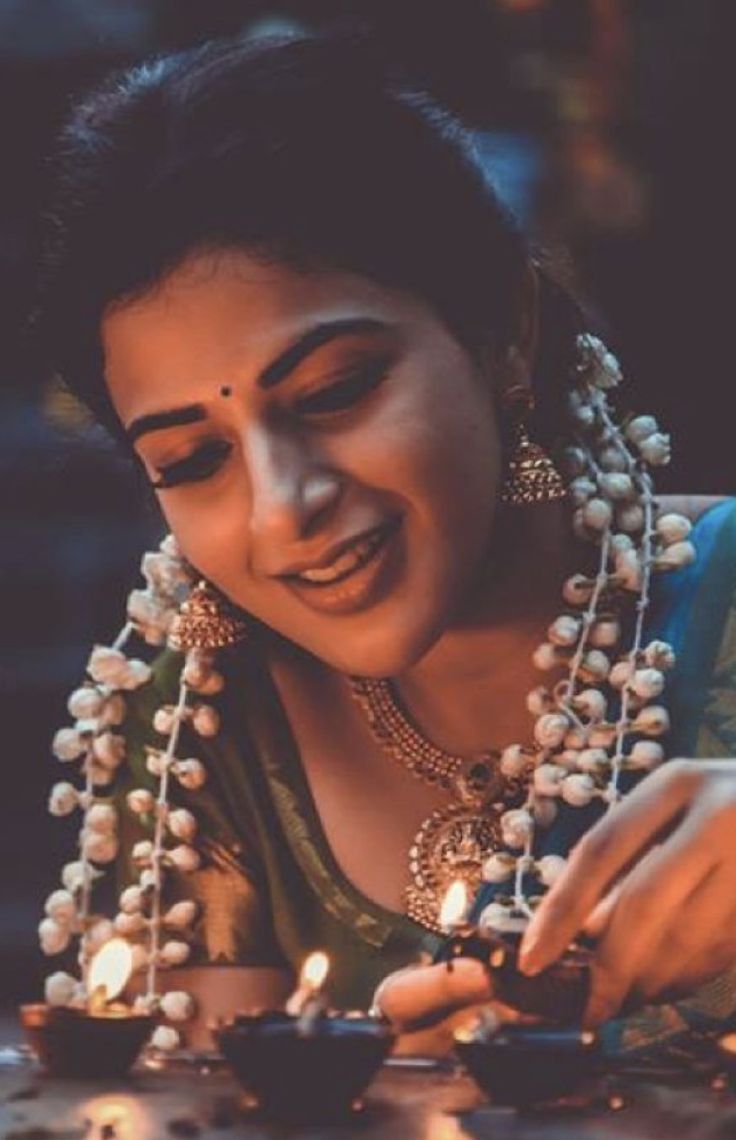 a woman is smiling while lighting candles in her hand and looking down at the ground