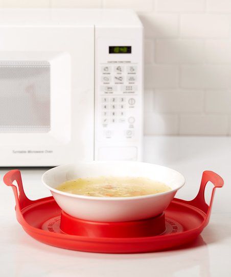 a bowl of soup is sitting on a blue plate in front of a white microwave