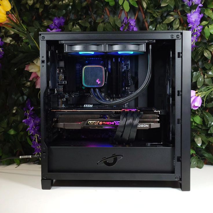 a black computer case sitting on top of a white table next to purple and yellow flowers