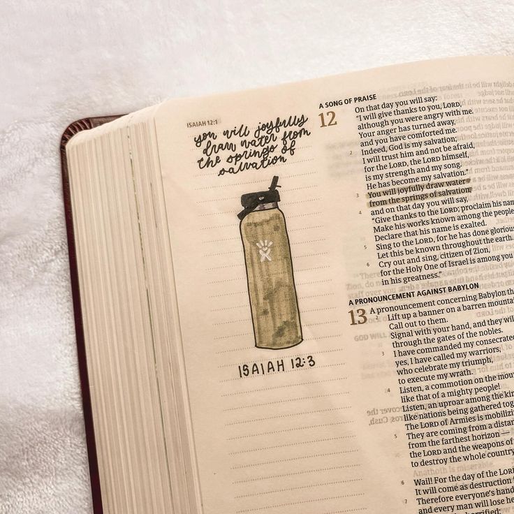 an open book with the contents of a water bottle on it, sitting on top of a bed