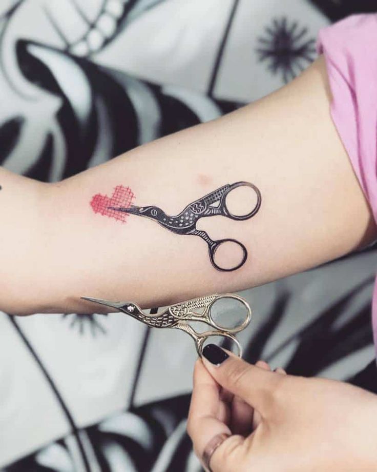 a woman with a tattoo on her arm holding scissors