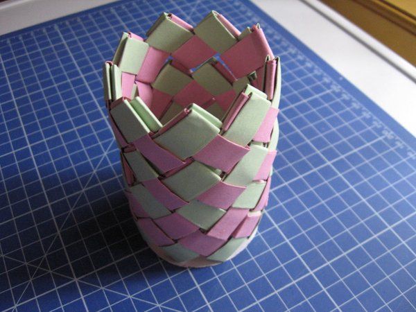 a pink and green vase sitting on top of a blue cutting mat next to a knife