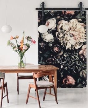 a dining room table and chairs with flowers on the wall