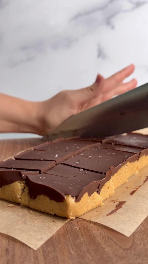 someone is cutting into a chocolate bar with a large knife on it's side