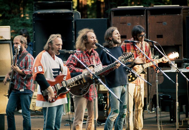 a group of men standing on top of a stage next to each other holding guitars