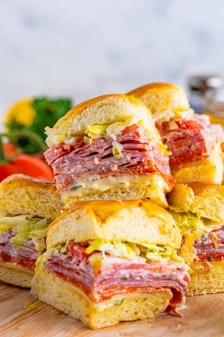 a pile of sandwiches sitting on top of a wooden cutting board