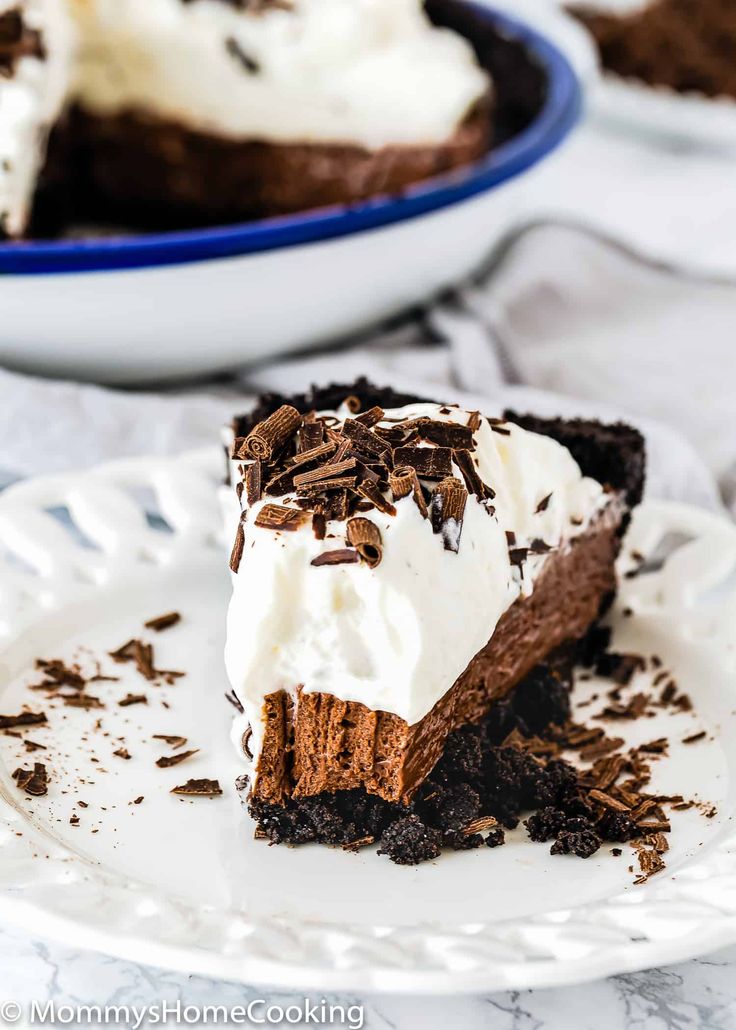 a slice of chocolate ice cream pie on a plate with the rest of the pie in the background