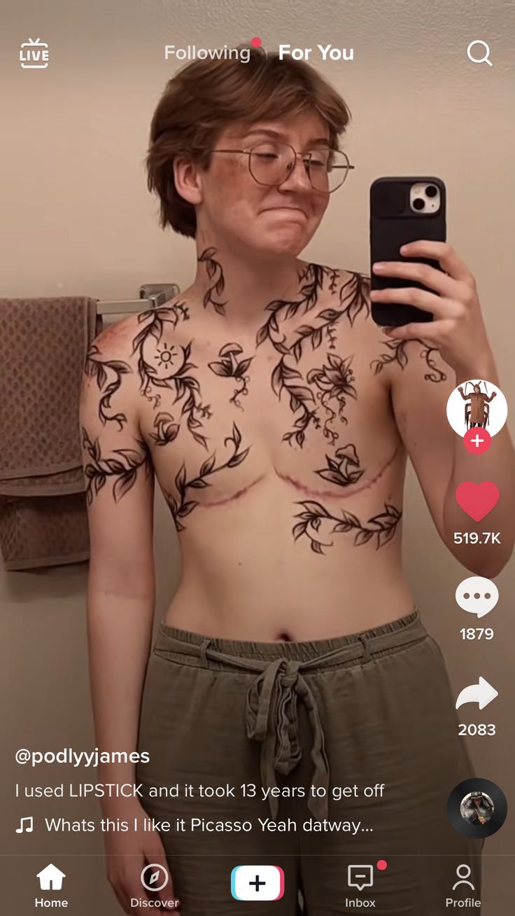 a woman with tattoos on her chest taking a selfie