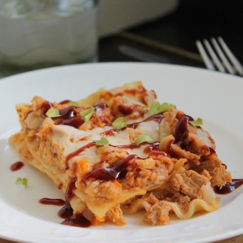 a white plate topped with lasagna covered in sauce