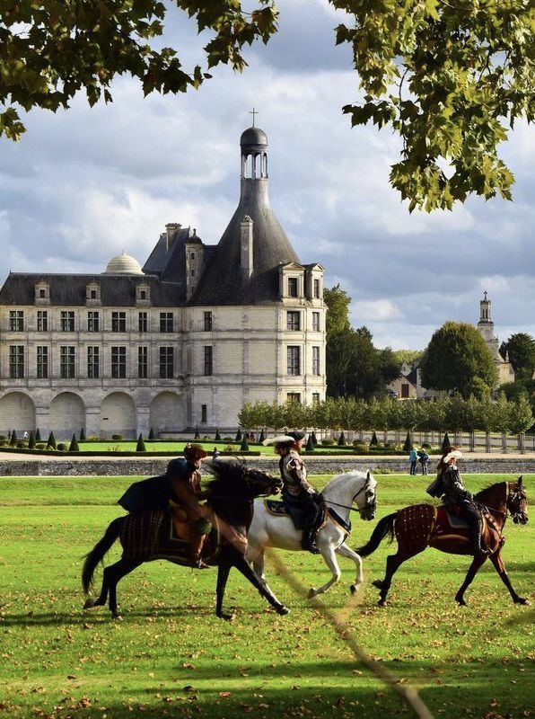 three men riding horses in front of a large building