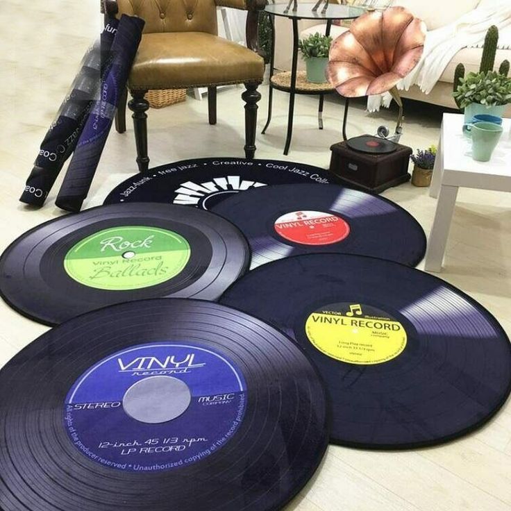 four different colored records on the floor next to a chair and table in a living room