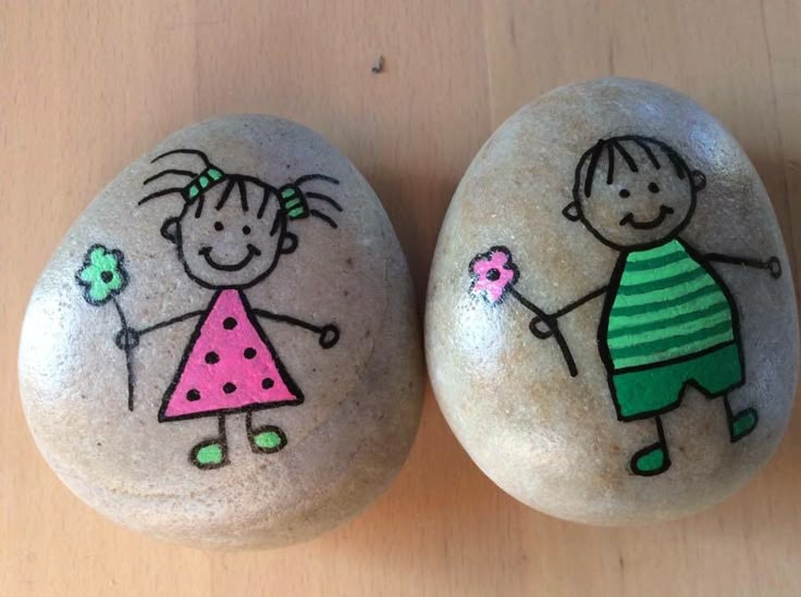 two rocks painted with children's drawings on them, one is holding a flower