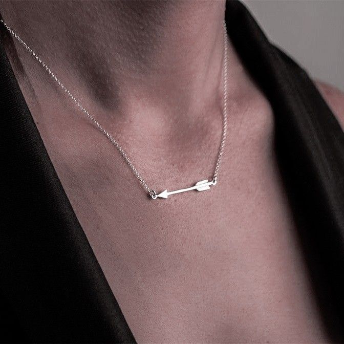 a woman wearing a necklace with two arrows on it's back and one arrow in the middle