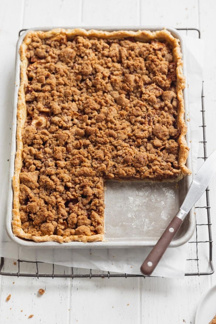 a baked dessert sitting on top of a cooling rack next to a knife and fork