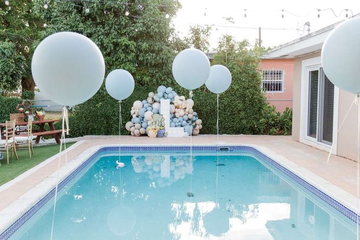 balloons floating in the air next to a swimming pool