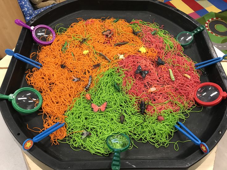 a black tray filled with lots of different colored noodles and plastic magnifying glasses