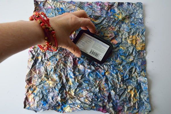 a hand holding a cell phone next to a piece of paper that has been torn off