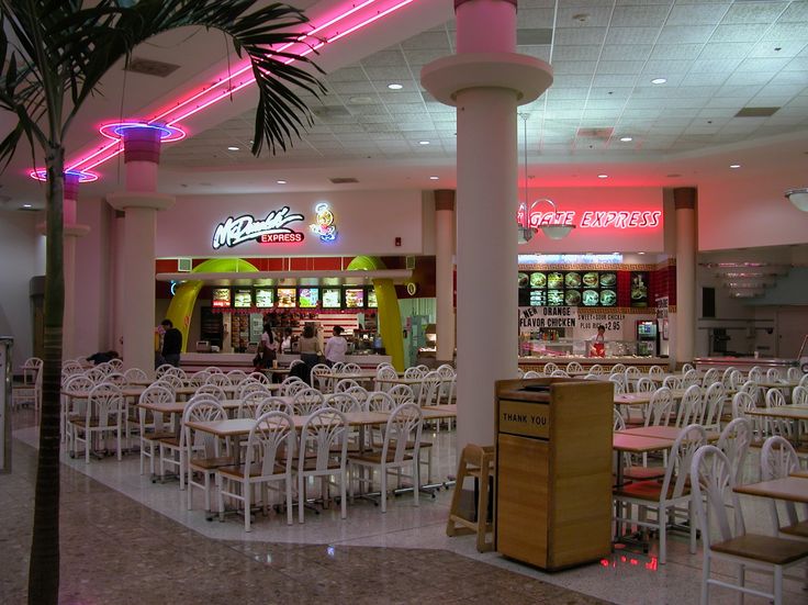 the inside of a restaurant with white tables and chairs, neon lights on the ceiling