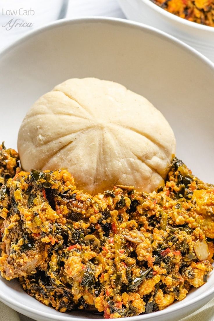 a bowl filled with food next to a roll on top of a white table cloth