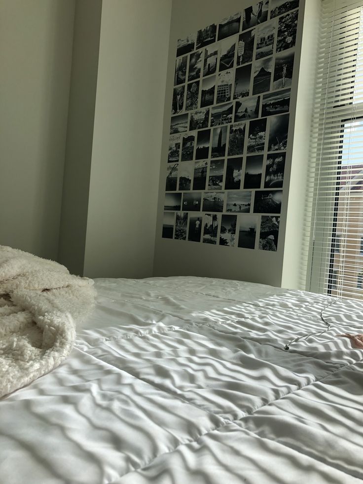 an unmade bed with white sheets and pictures on the wall behind it in a bedroom