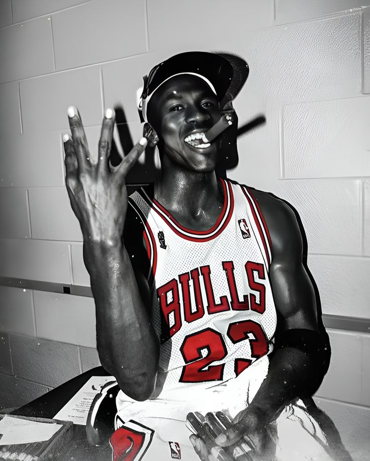 a black and white photo of a basketball player holding his hands up in the air