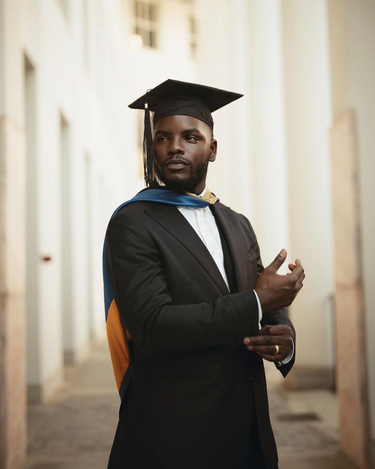 a man in a graduation cap and gown is posing for a photo with his hand on his hip