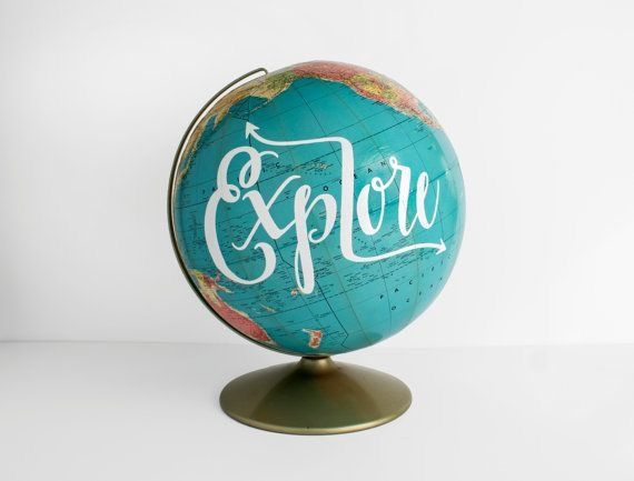 an old globe with the word explore painted on it, sitting on a white surface