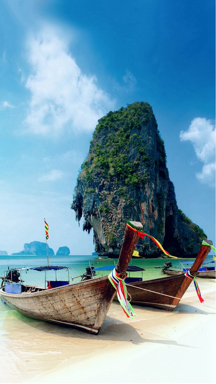 two boats on the beach with an island in the background