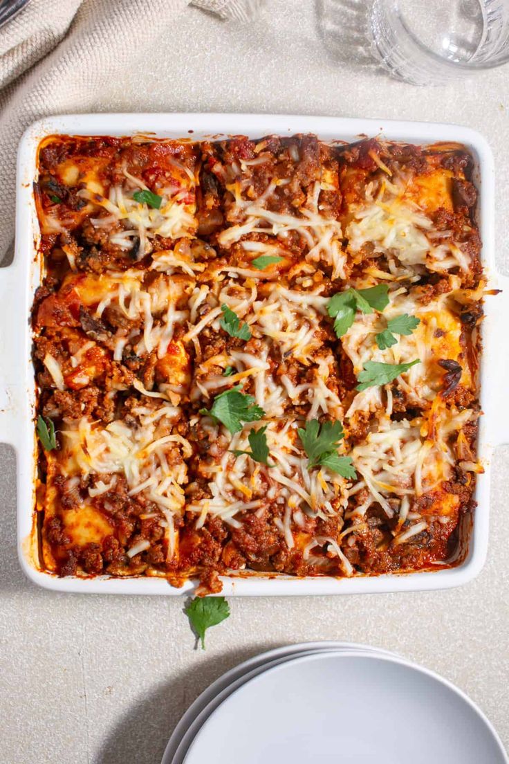 a casserole dish with meat, cheese and parmesan on the side